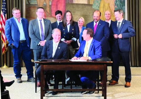 Rep. Neil Riser (seated left) and Governor Jeff Landry (seated right)